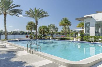 A swimming pool in front of a building with palm trees